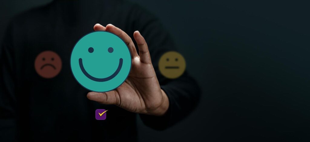 A person holding up a smiling emoji to symbolize a happy customer. 